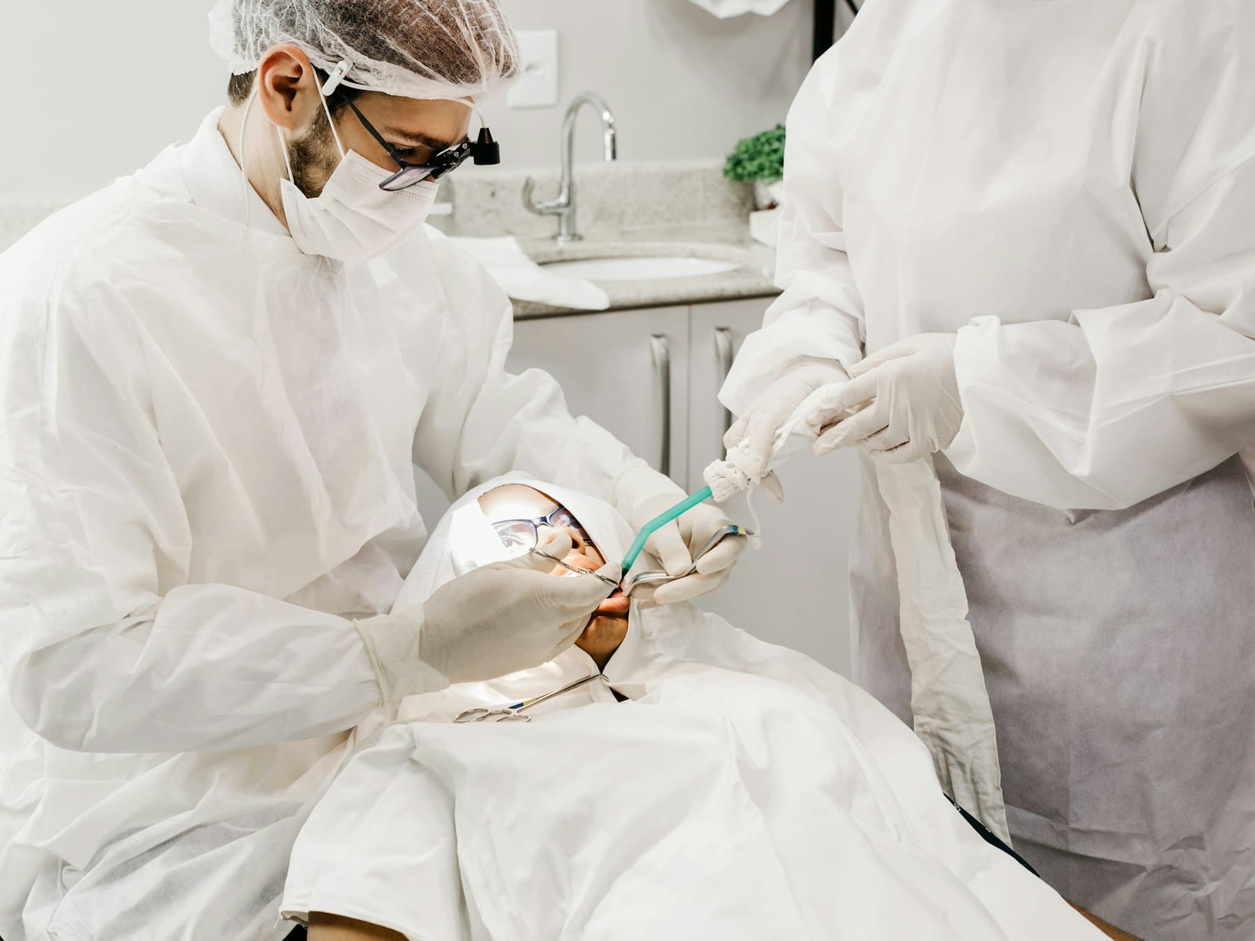 One clinician working at the chair while a second stands alongside, passing an instrument